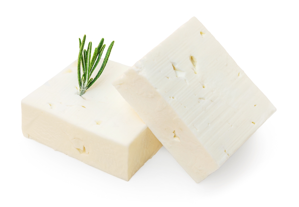 Feta cheese isolated. Greek fitaki cheese pieces on white background with rosemary herbs. Top view
