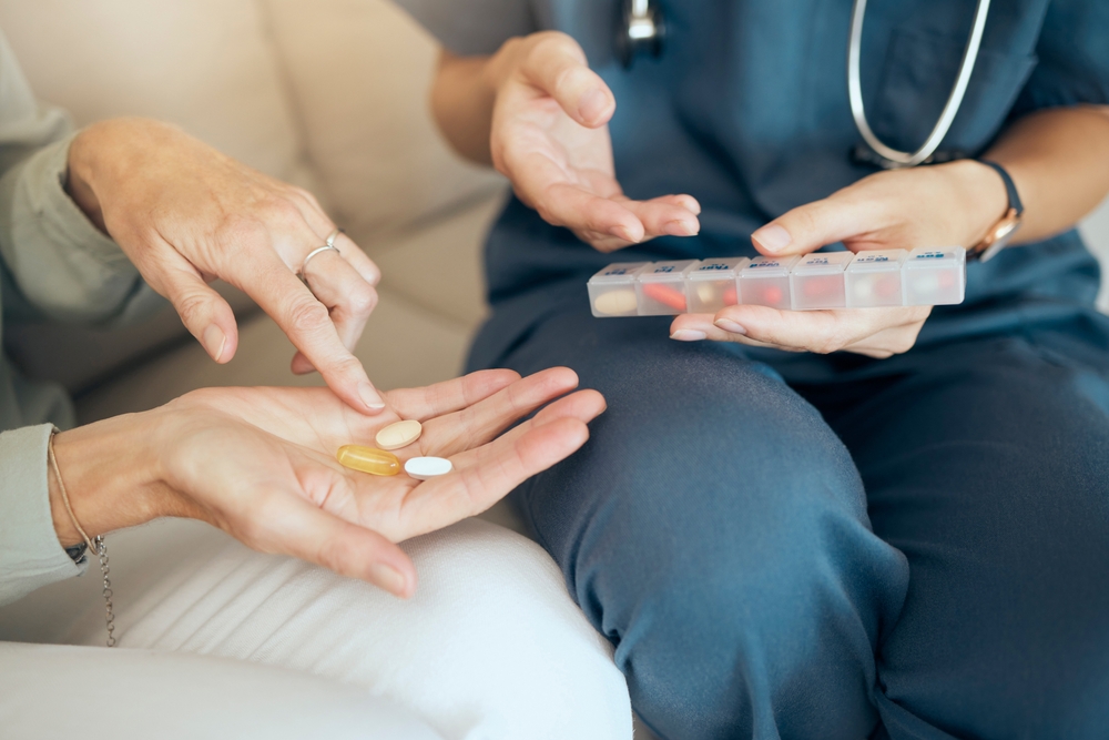 Senior care, woman and nurse with pills in house, illness management and discussion with medication. Nursing home, medical insurance and caregiver for hands, pharmaceutical and wellness service