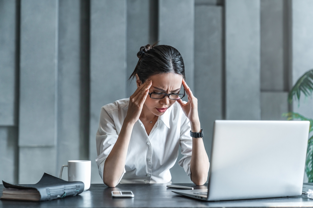 Young woman working on laptop having headache. Bored workaholic female accountant employee with headache and stress. Businesswoman woman with migraine, stress relief, chronic pain