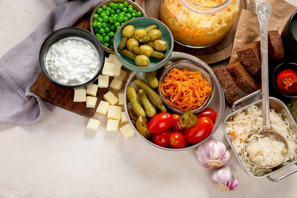 Probiotic food concept. Cabbage in jar, pickle, carrot on light wooden background. Top view, copy space