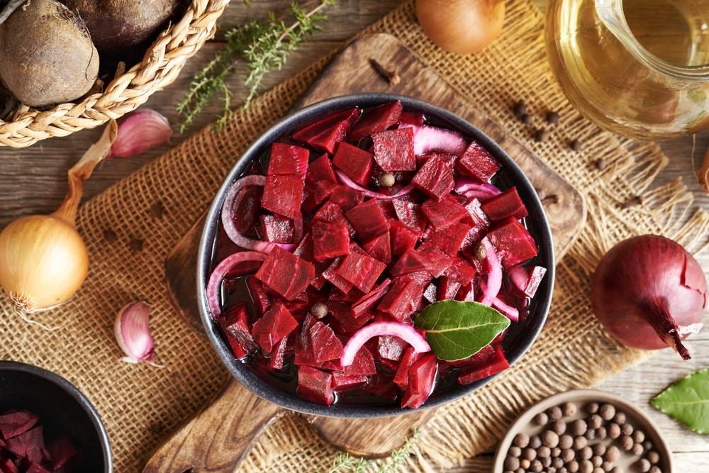 Fermented red beet kvass in a black bowl with onions, garlic bay leaf and allspice, top view