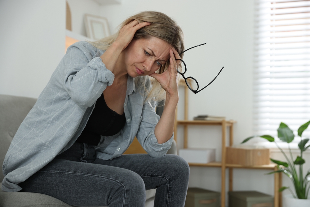 Menopause. Woman suffering from headache on sofa at home
