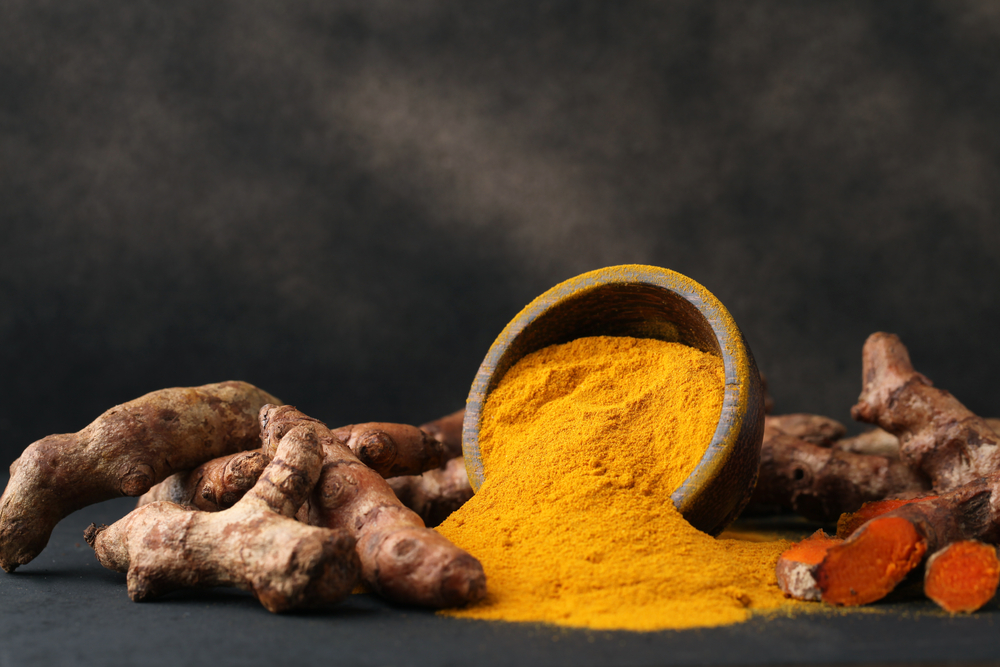 Turmeric powder and fresh turmeric on wooden background.with copy space.