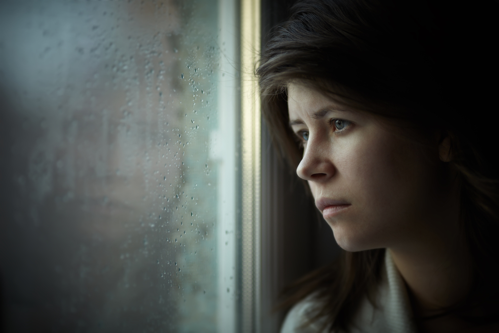 lonely girl near window thinking about something
