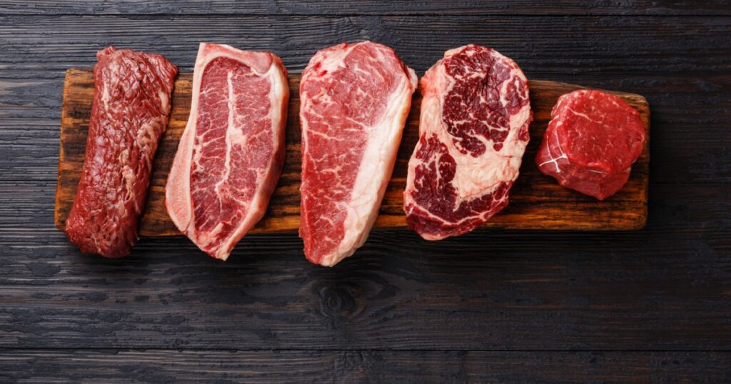 Variety of Raw Black Angus Prime meat steaks Machete, Blade on bone, Striploin, Rib eye, Tenderloin fillet mignon on wooden board copy space