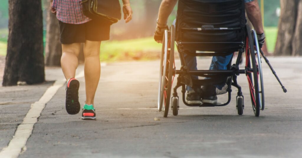 A man on wheelchair and his wife enjoying in the park,copy space.