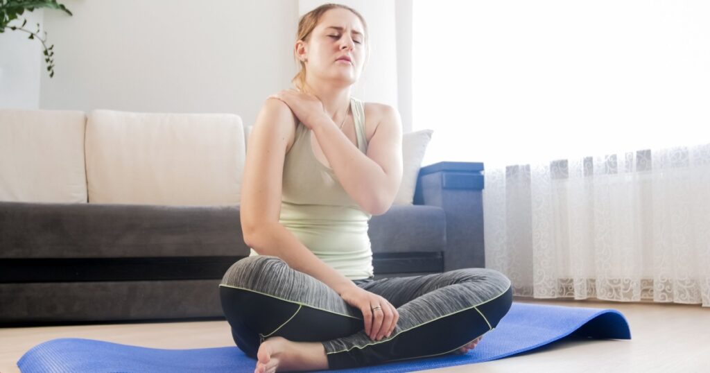 Woman feeling pain in shoulder after exercising at home