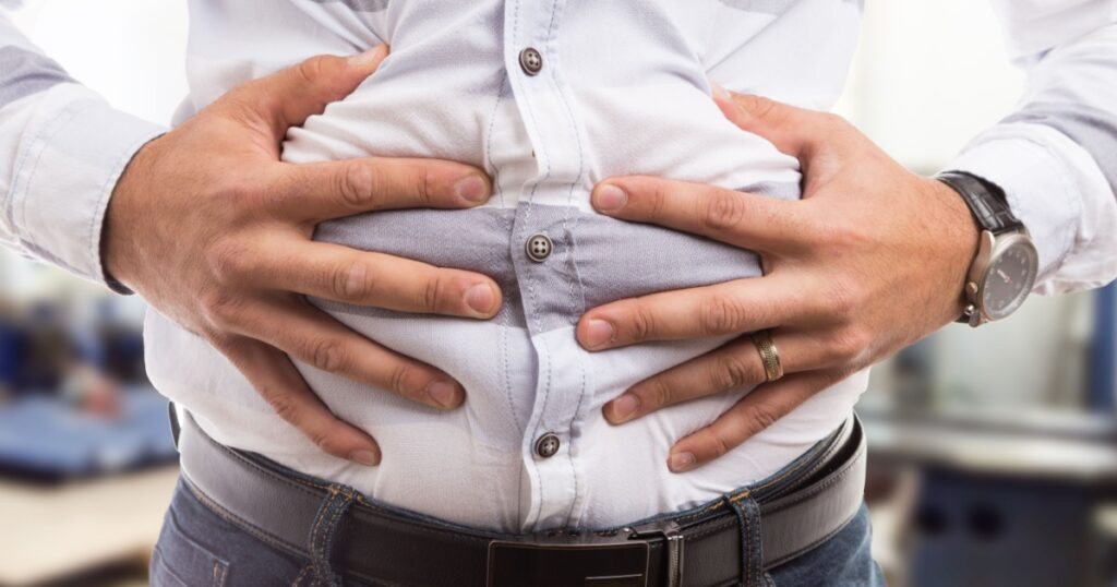 Man pressing grabbing bloated abdomen or belly as cramp flatulence constipation problem