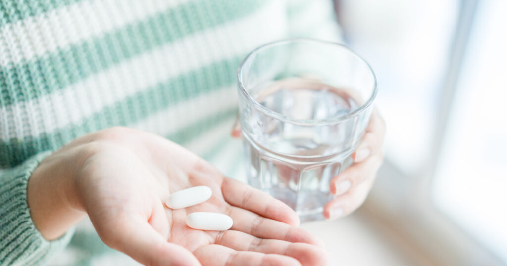 Close Up Of Girl holding Pill and glass of