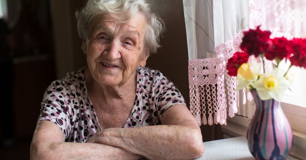 Elderly woman portrait near window in the house.