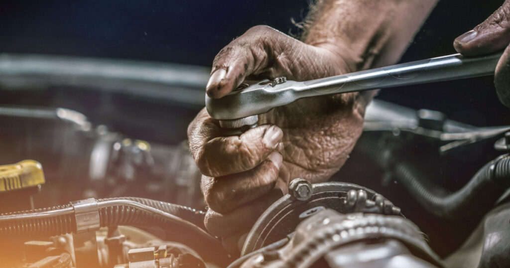 Auto mechanic working on car engine in mechanics garage. Repair service. authentic close-up shot