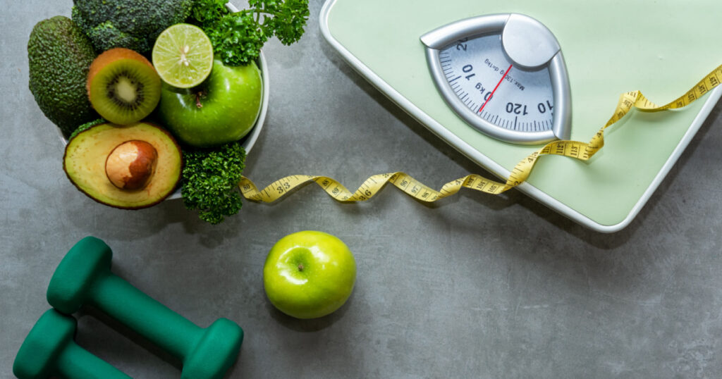 Diet and Healthy life loss weight slim Concept. Organic Green apple and Weight scale measure tap with nutrition vegan vegetable and sport equipment gym for body women diet fit. Top view copy space.