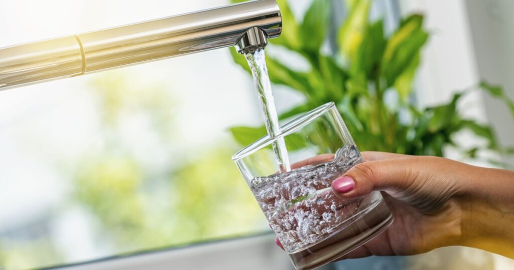 woman hand holds a glass to Filing it with water from tap
