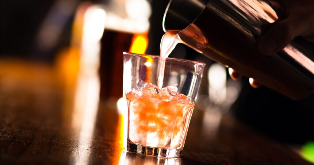 Barman pouring a cocktail into a glass