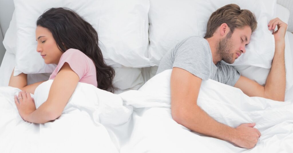 Beautiful couple sleeping back to back in their bed