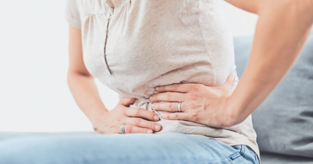 Woman with stomach issues / problems while lying on the couch.