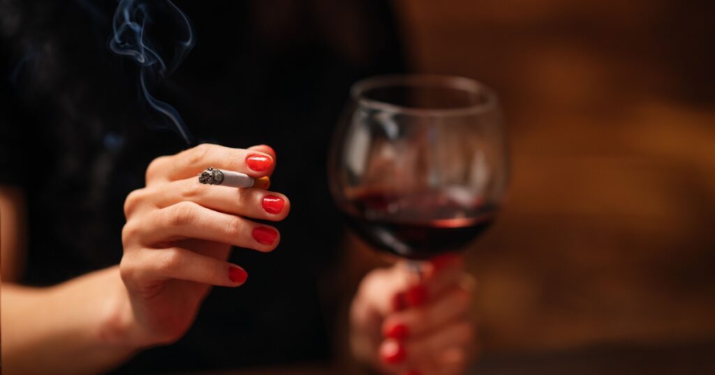 Lonely beautiful woman sitting on the bar, smooking cigarette and drink wine.