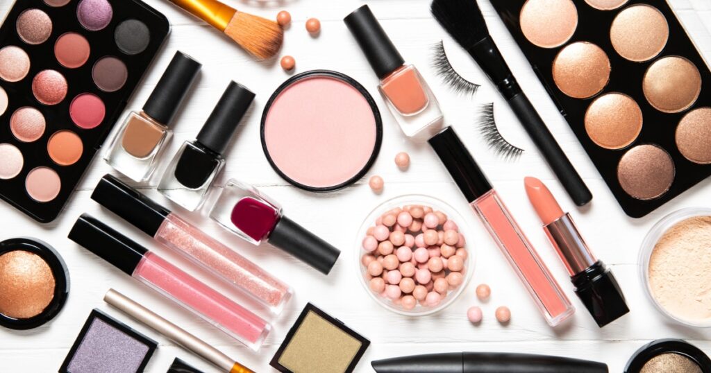 Decorative cosmetics and makeup brushes on a white background, top view