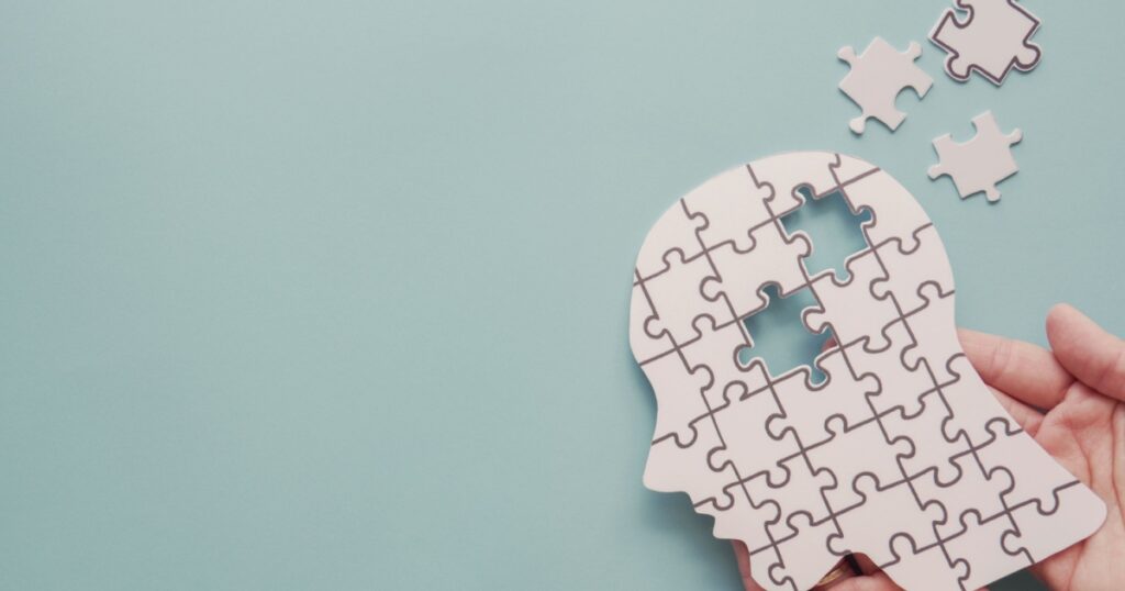 Hands holding brain with puzzle paper cutout, autism, memory loss, dementia, epilepsy and alzheimer awareness, world mental health day, world Parkinson day concept