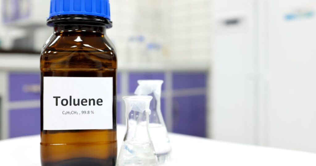 Selective focus of toluene liquid chemical compound in dark glass bottle inside a chemistry laboratory with copy space. Aromatic hydrocarbon used in petrochemical industry.
