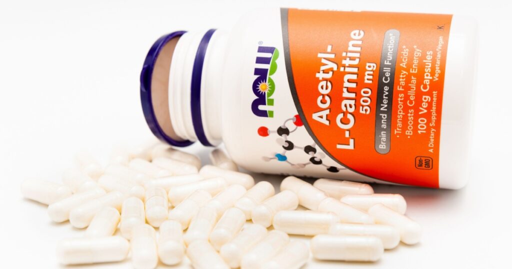 Fuji City, Shizuoka-Ken, Japan - November 7, 2020: Now Foods, Acetyl-L-Carnitine, 500 mg, 100 Veg Capsules and several scattered in front of the bottle. Isolated on white background.