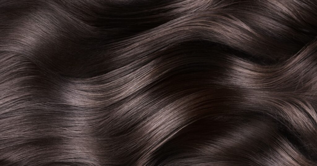 A closeup view of a bunch of shiny curls brown hair.