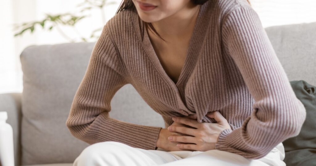 Flatulence young asian woman, girl hand in stomach ache, suffer from food poisoning, abdominal pain and colon problem, gastritis or diarrhoea. Patient belly, abdomen or inflammation, concept.