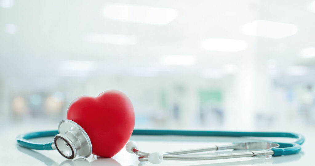 Red heart love shape hand exercise ball with doctor physician's stethoscope on hospital background: Hospital life insurance concept: World heart health day. doctor day, world hypertension day