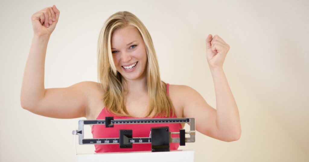 Cheering woman standing on scale