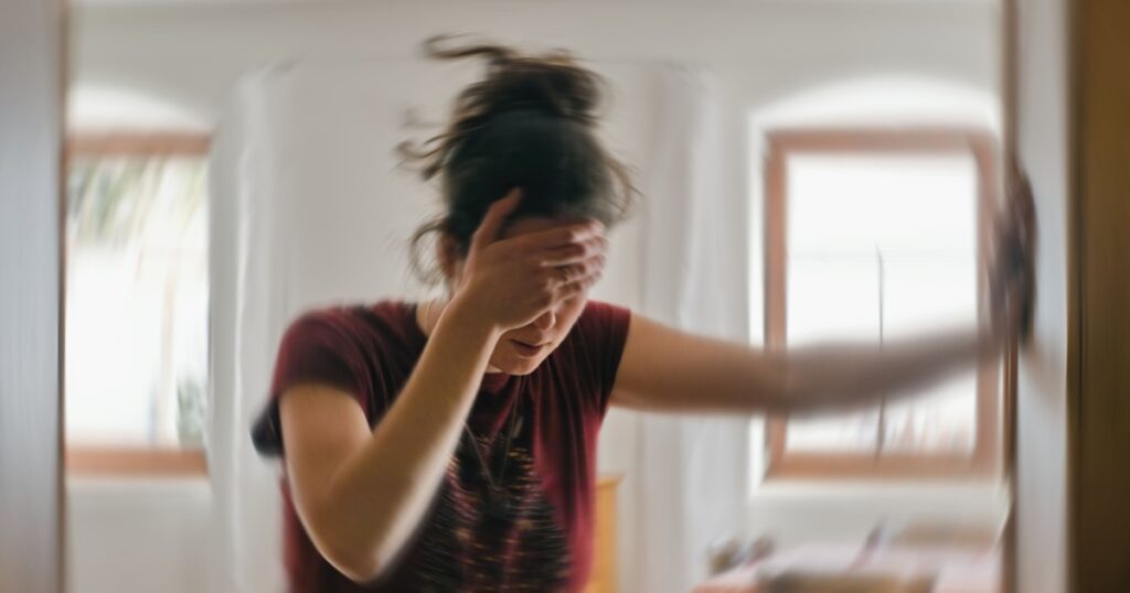 Blured photo of a woman suffering from vertigo or dizziness or other health problem of brain or inner ear.
