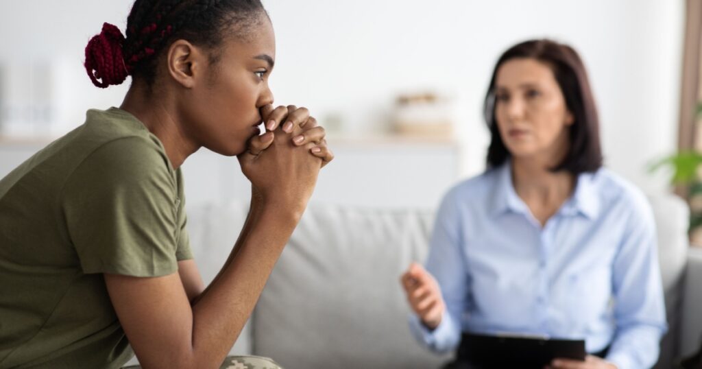 Upset Pensive Black Military Lady Having Therapy Session With Psychologist In Office, African American Soldier Woman Suffering Mental Illness Or Posttraumatic Stress Disorder, Selective Focus