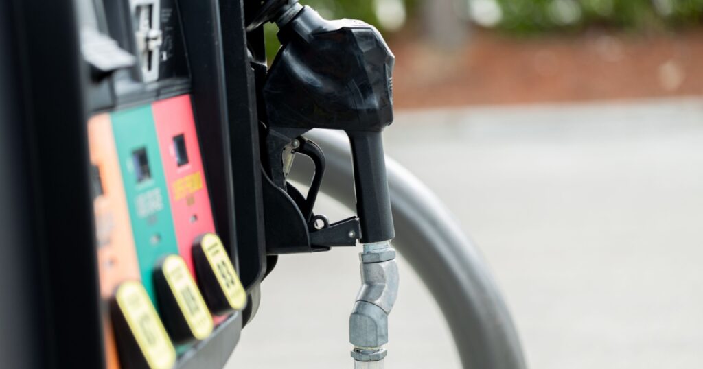 Gas pump at an American gas station with a black nozzle and colorful fuel option buttons oil petrol gasoline