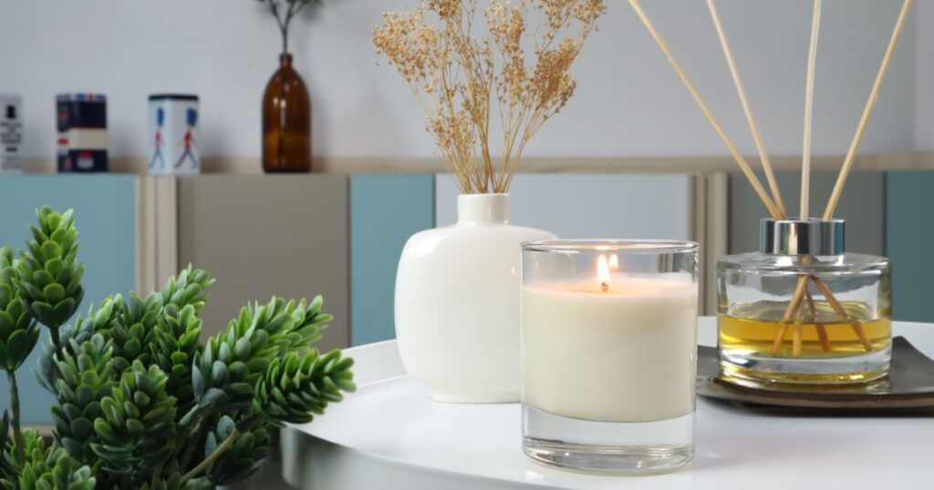 luxury lighting aromatic scented candle is on white metal table with ceramic vase and reed diffuser to creat relax ambient in the bedroom with background of nice bedroom and curtain on Valentine day
