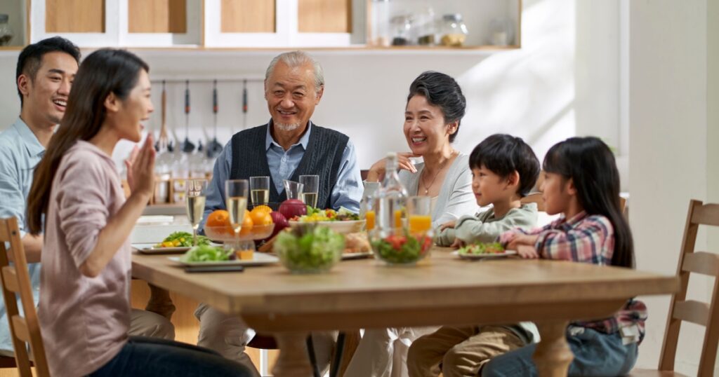 multi generational asian family chatting while having meal together at home