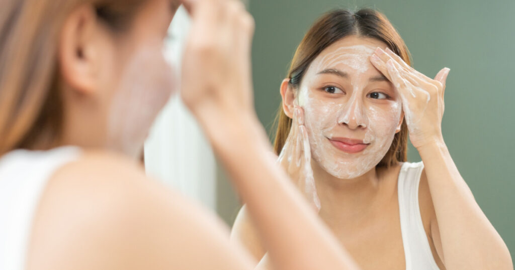 Cheerful asian young woman, beauty girl hand applying foam cleanser for washing on her face, clean fresh healthy skin care, exfoliation scrub soap with cleansing product. Skincare spa relax concept.