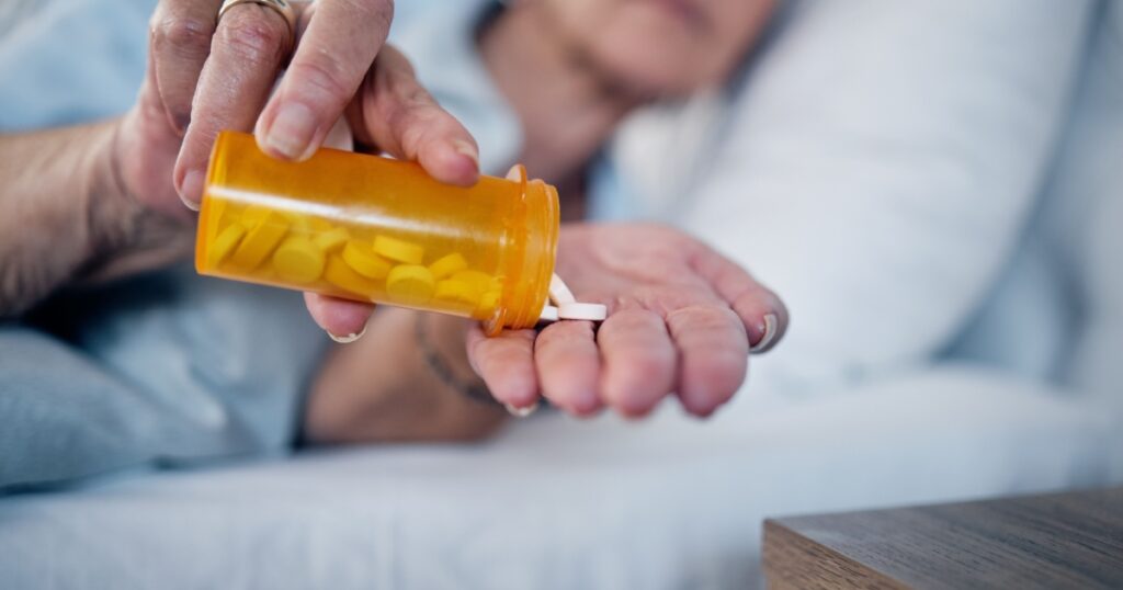 Insomnia pills, depression and senior woman in bed sleeping for pharmaceutical, psychology or mental health. Depressed, addiction and medicine of sick elderly person, drugs help or risk in bedroom