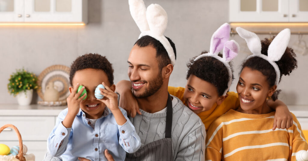 Happy African American family with Easter eggs at table in kitchen