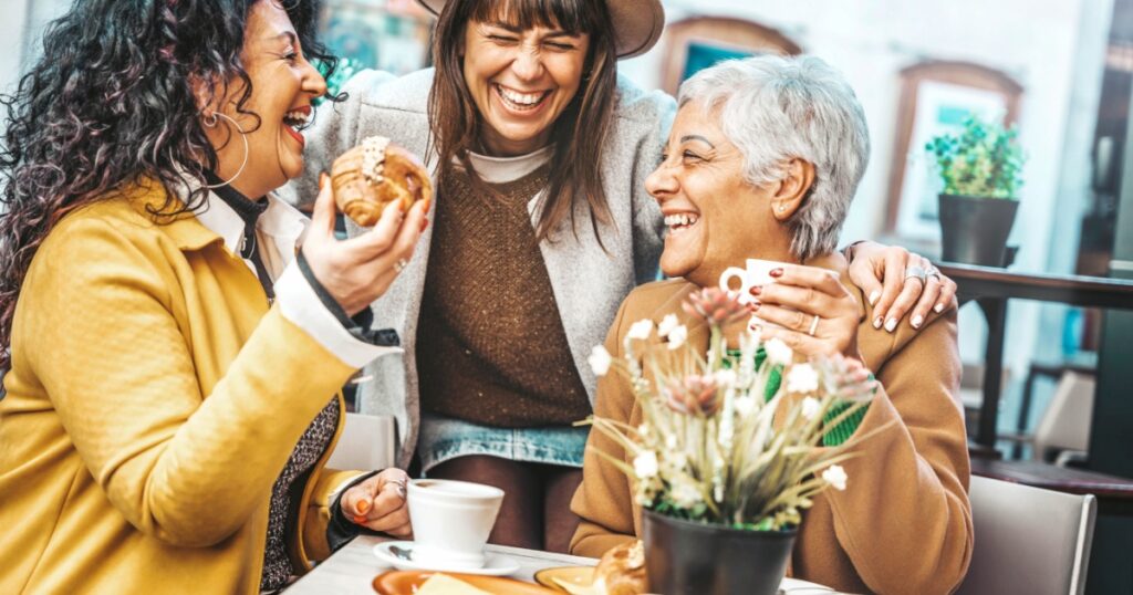 Three senior women enjoying breakfast drinking coffee at bar cafeteria - Life style concept with mature female having fun hanging out on city street