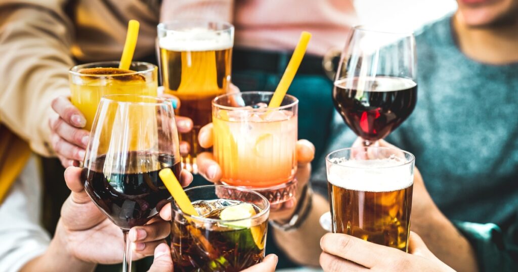 Friends hands toasting fancy cocktails - Young people having fun together drinking beer and wine at happy hour - Social life style party time concept on vivid filter - Focus on lower cuba libre drink