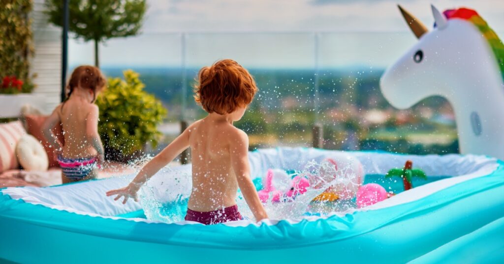 excited kids having fun in inflatable pool on summer patio. jumping and splashing around