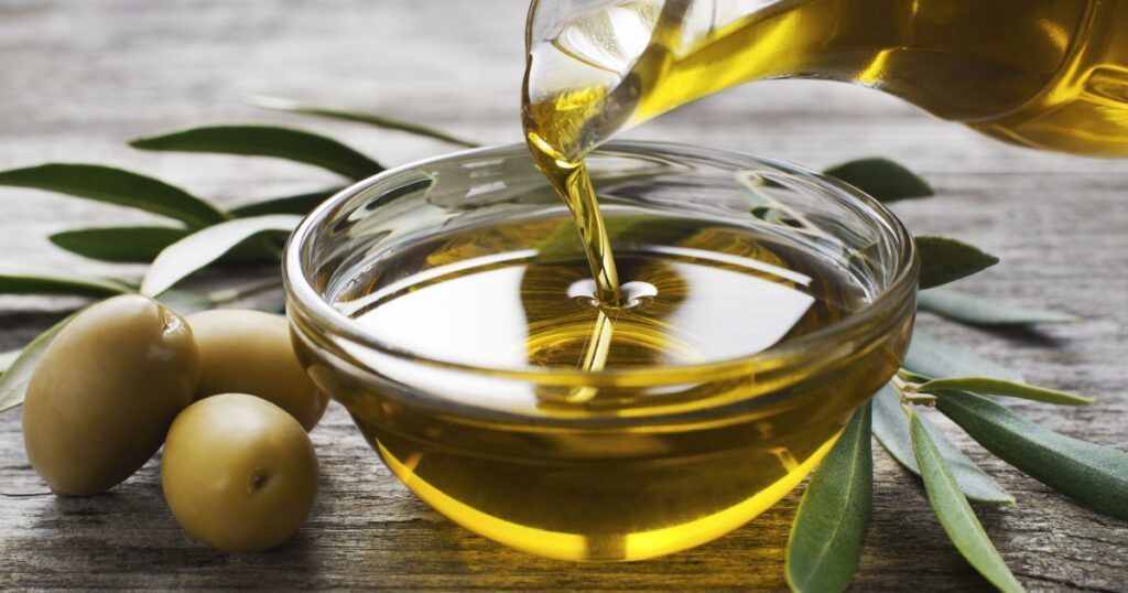 Bottle pouring virgin olive oil in a bowl close up