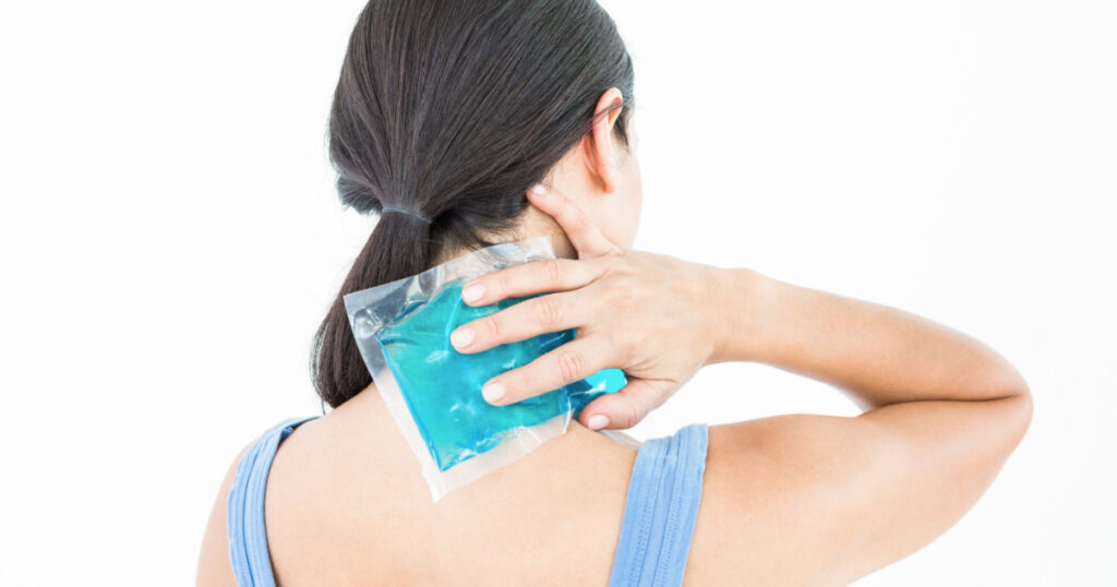 Beautiful brunette putting gel pack on neck on white background