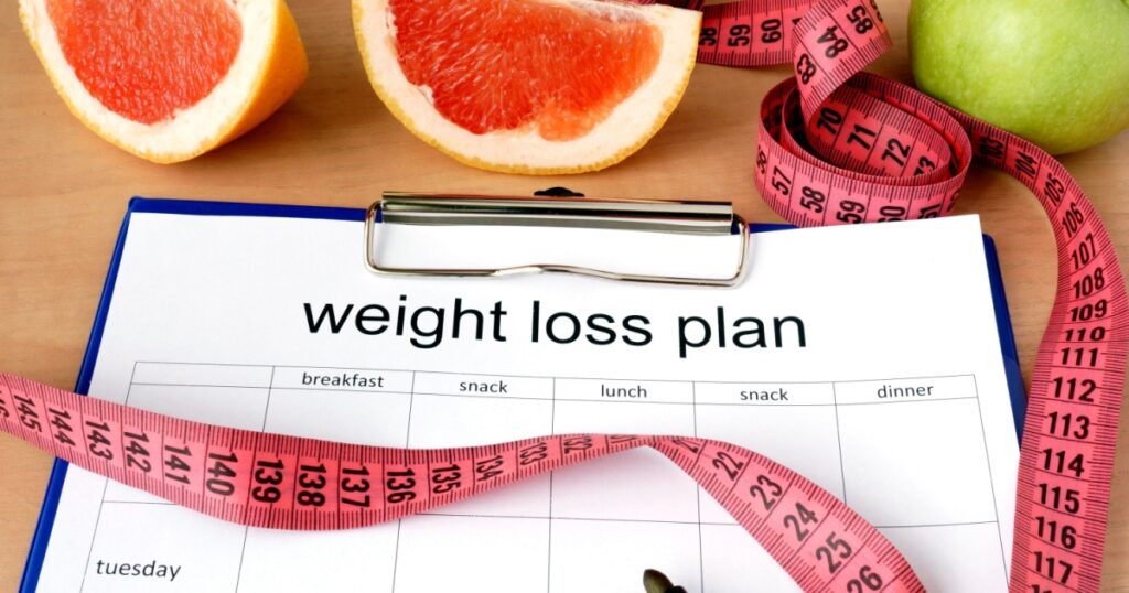 Paper with weight loss plan and grapefruit
