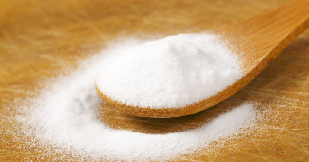 spoon of cooking soda on wooden cutting board