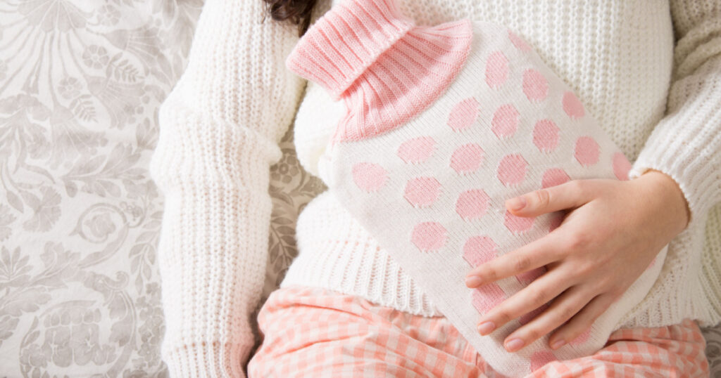 Young woman with hot-water bottle on belly