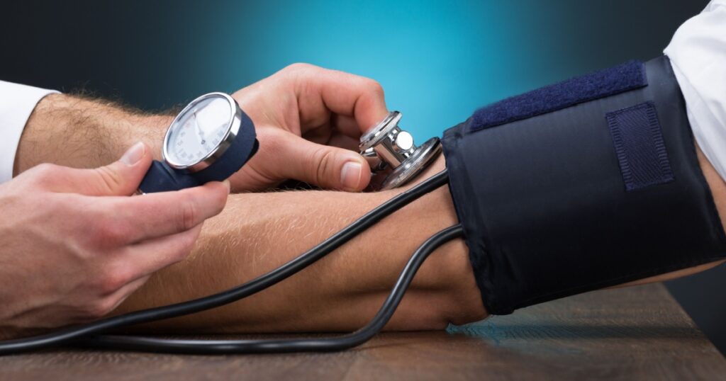 Cropped image of male doctor checking blood pressure of patient at table