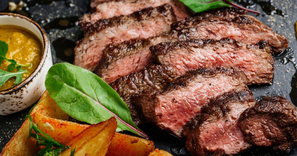 Juicy Beef rump steak from marble beef medium rare with potatoes and sauce on stone plate, close-up. Selective focus.