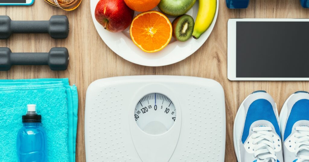 Sports and workout equipment, digital tablet and fruit on a wooden table, training and healthy lifestyle concept, flat lay