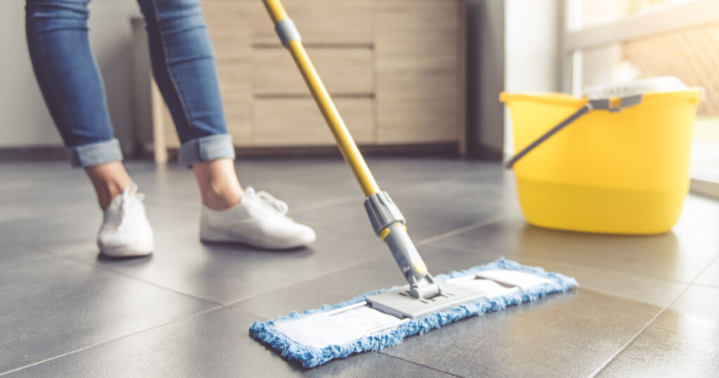 Cropped image of beautiful young woman in protective gloves using a flat wet-mop while cleaning floor in the house