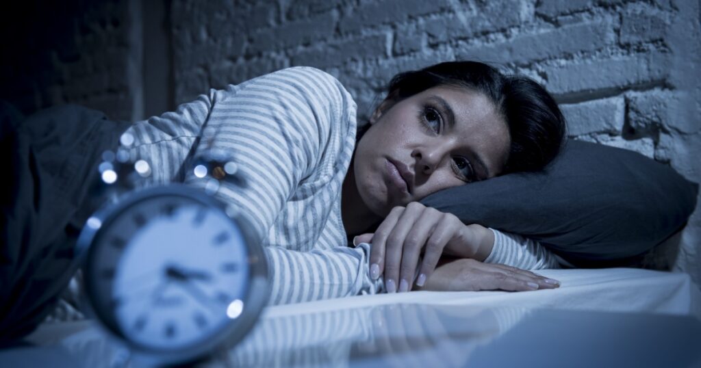 young beautiful hispanic woman at home bedroom lying in bed late at night trying to sleep suffering insomnia sleeping disorder or scared on nightmares looking sad worried and stressed